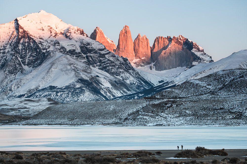 Two photographers working at dawn before the Torres del Paine, lit in alpenglow